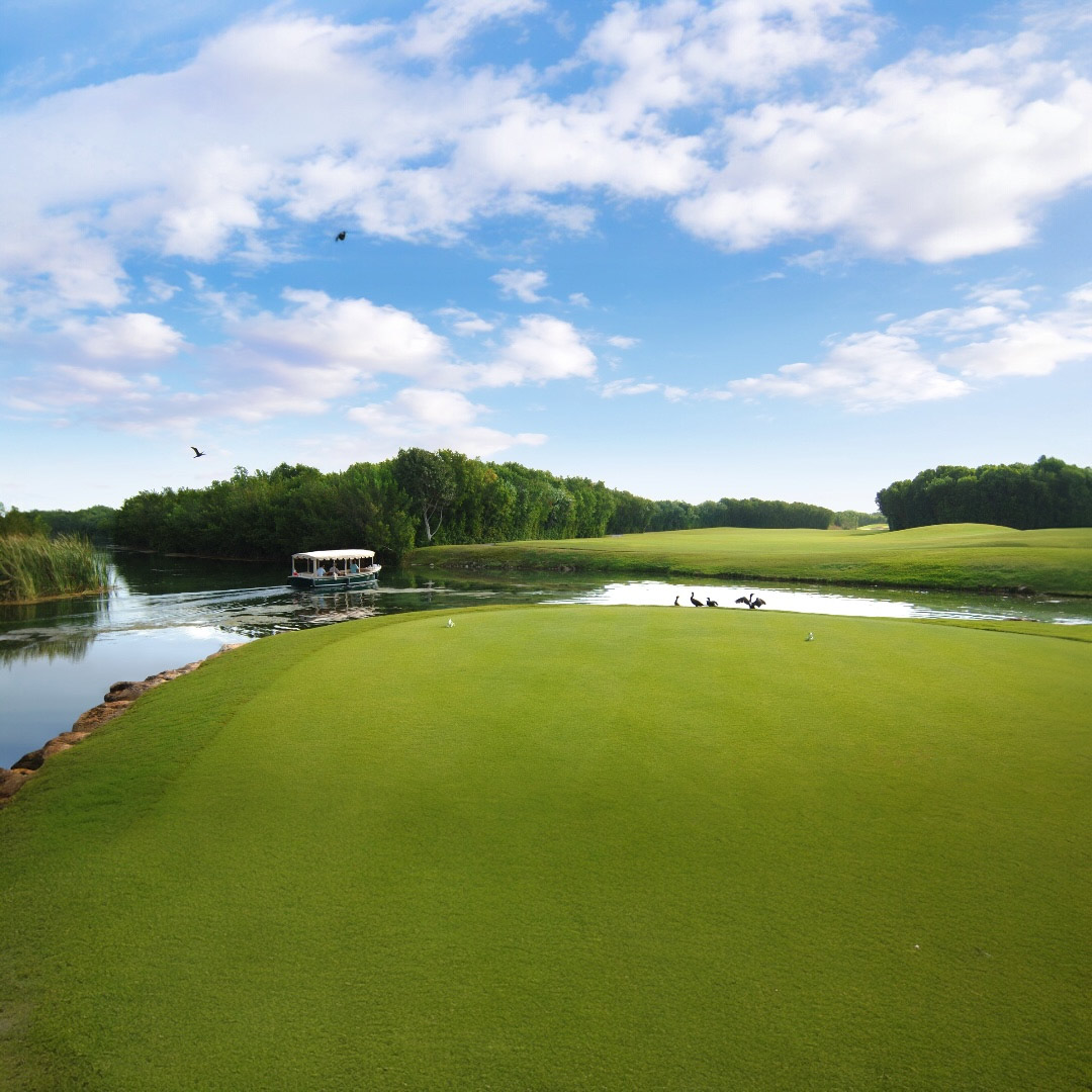 Scenic golf course with lagoon and electric boat at The Reserve at Mayakoba