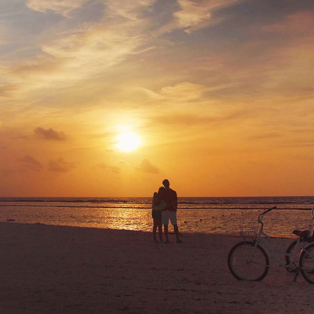 Persona en bicicleta contemplando el atardecer en la playa de The Reserve at Mayakoba, Riviera Maya